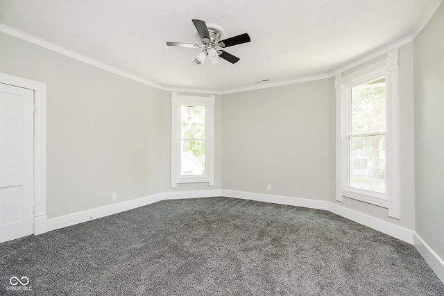 spare room featuring a wealth of natural light, dark colored carpet, and ornamental molding