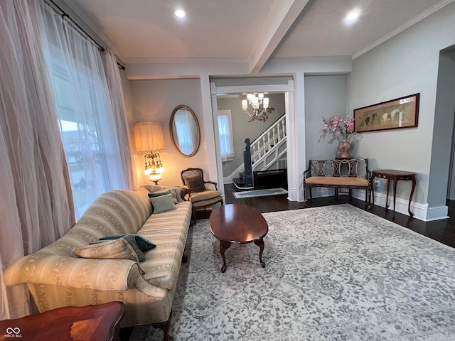 living room with dark wood-type flooring, beam ceiling, an inviting chandelier, and crown molding