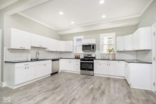 kitchen with white cabinets, sink, appliances with stainless steel finishes, and ornamental molding