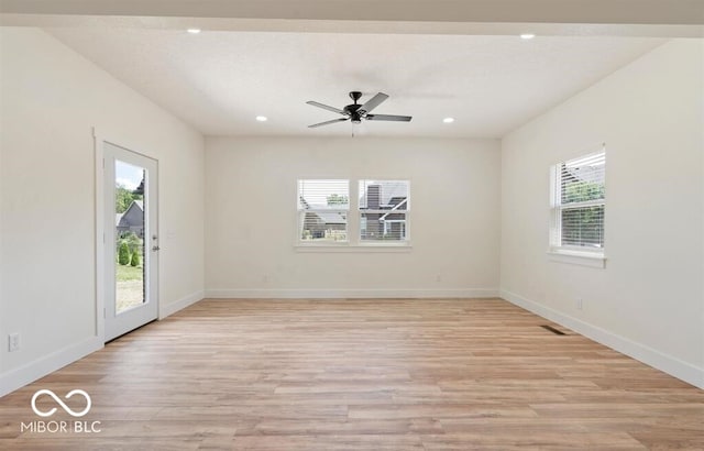 spare room featuring a wealth of natural light, ceiling fan, and light hardwood / wood-style floors