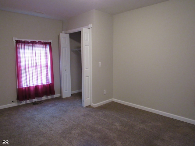 unfurnished bedroom with a closet and dark colored carpet