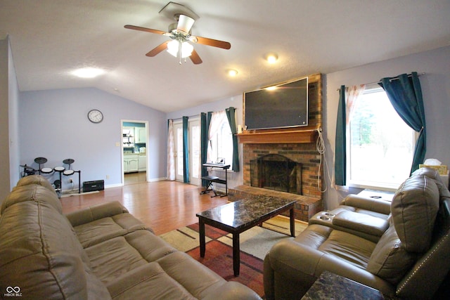 living room with a fireplace, light hardwood / wood-style floors, ceiling fan, and vaulted ceiling