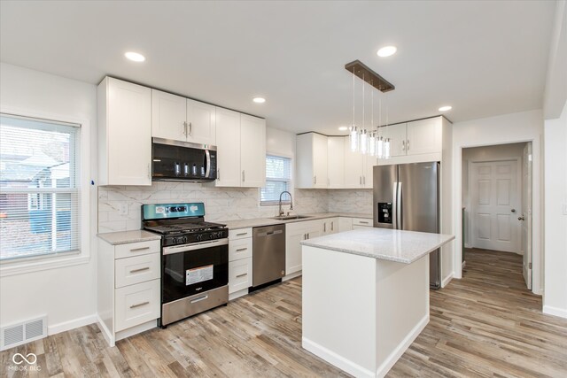 kitchen featuring sink, white cabinetry, a kitchen island, pendant lighting, and stainless steel appliances