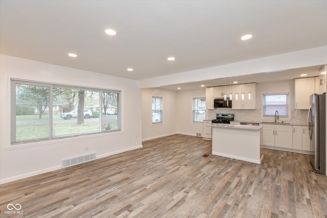 kitchen featuring sink, range, decorative light fixtures, stainless steel fridge, and white cabinets