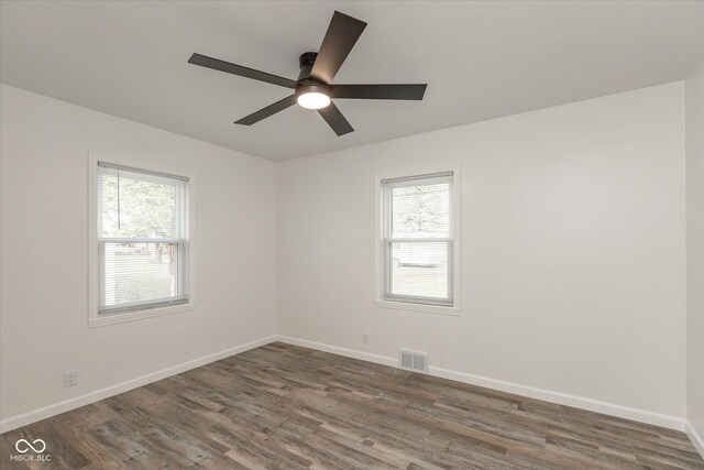 spare room with a wealth of natural light, dark wood-type flooring, and ceiling fan