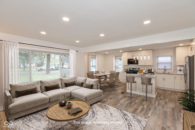 living room with sink, plenty of natural light, and light wood-type flooring