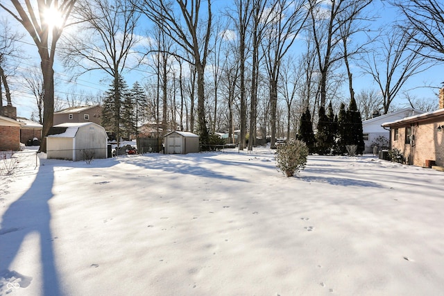 yard covered in snow with a storage shed