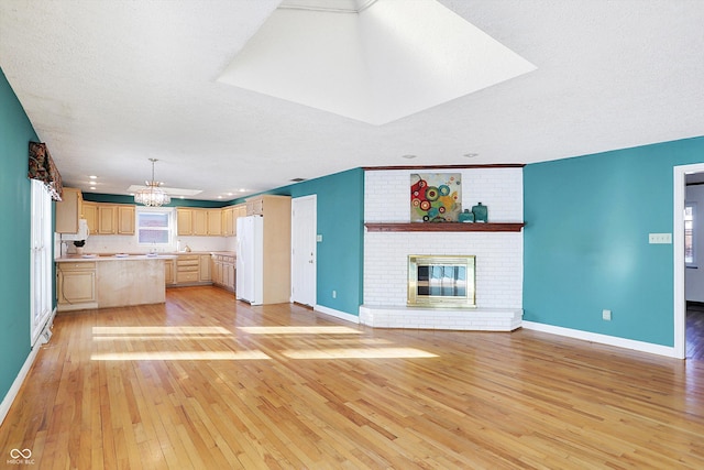 kitchen featuring a fireplace, light hardwood / wood-style flooring, a textured ceiling, light brown cabinetry, and white refrigerator