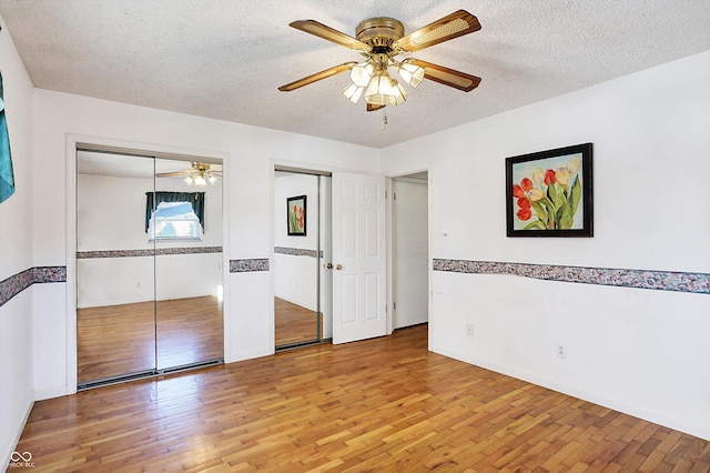 unfurnished bedroom with ceiling fan, wood-type flooring, and a textured ceiling