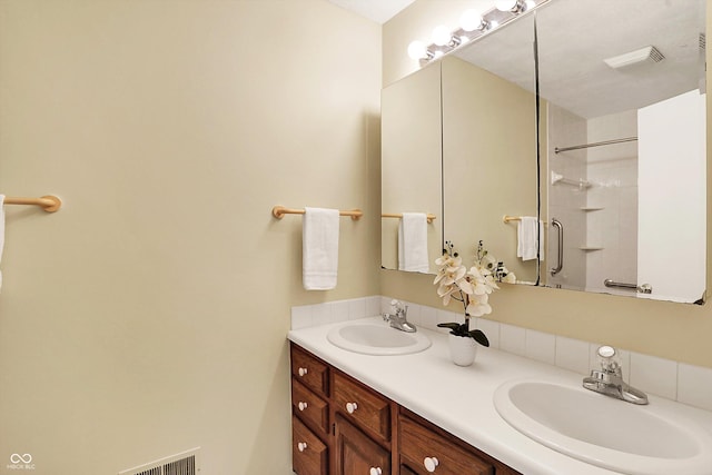 bathroom with a shower with shower door and vanity