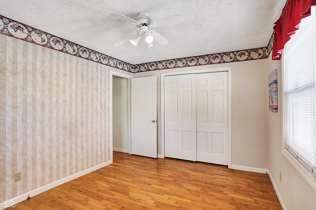 unfurnished bedroom featuring ceiling fan, a textured ceiling, light hardwood / wood-style flooring, and a closet