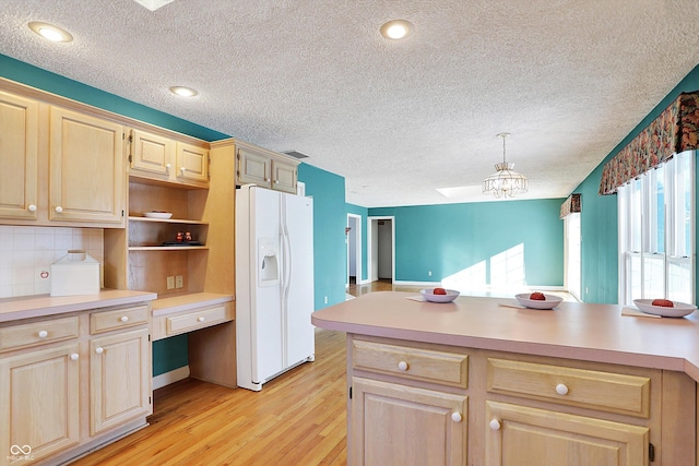 kitchen featuring backsplash, built in desk, light hardwood / wood-style flooring, hanging light fixtures, and white refrigerator with ice dispenser