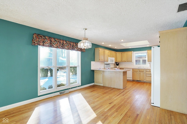 kitchen with white appliances, light hardwood / wood-style floors, sink, hanging light fixtures, and kitchen peninsula