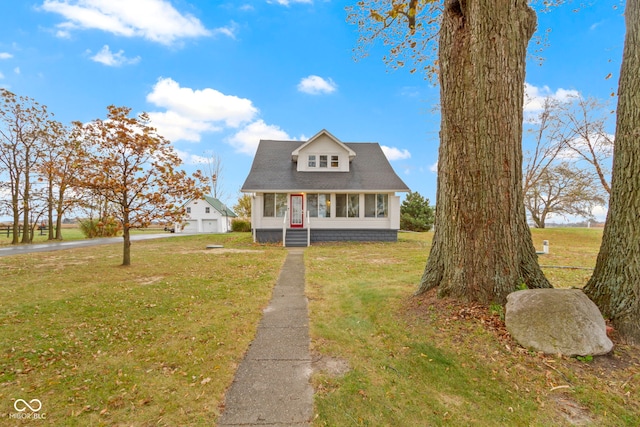 cape cod home with a garage, an outdoor structure, and a front lawn