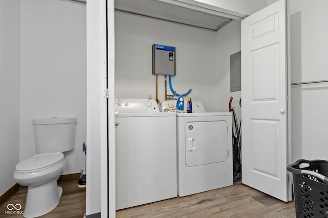 clothes washing area with light hardwood / wood-style floors, electric panel, and washing machine and clothes dryer