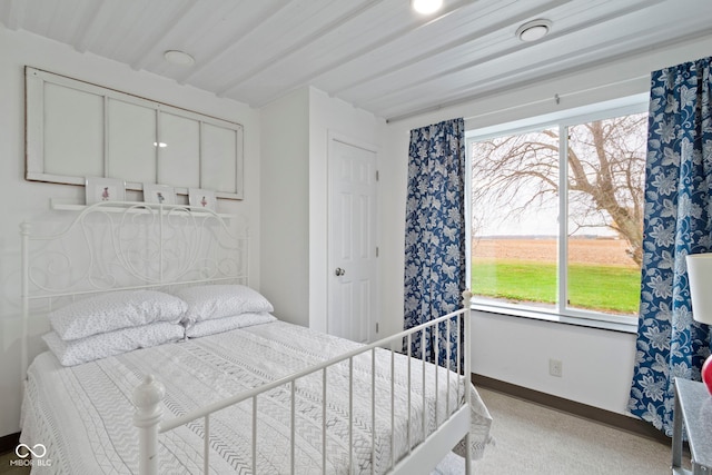 carpeted bedroom featuring beamed ceiling