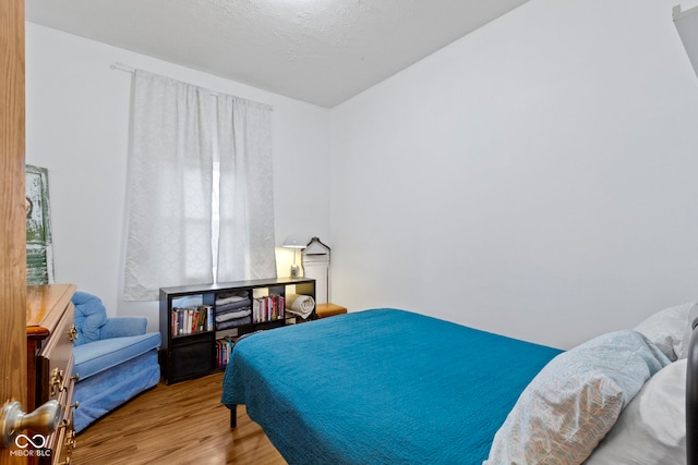 bedroom featuring light hardwood / wood-style flooring and a textured ceiling