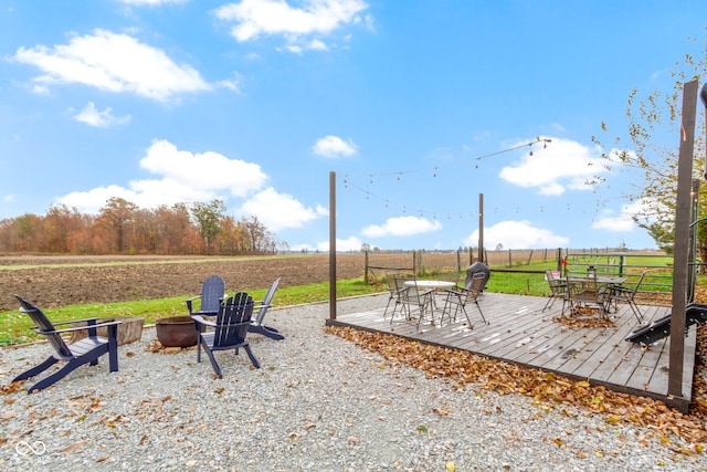 view of patio featuring a rural view, an outdoor fire pit, and a wooden deck