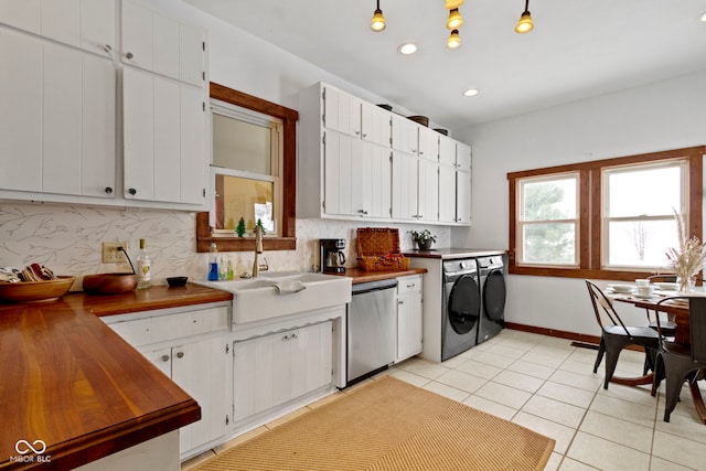 clothes washing area with light tile patterned floors, washer and clothes dryer, and sink