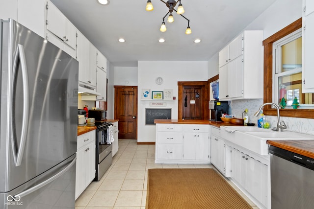 kitchen featuring white cabinetry, sink, wooden counters, light tile patterned floors, and appliances with stainless steel finishes