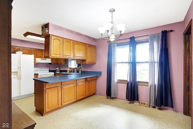 kitchen with an inviting chandelier, kitchen peninsula, sink, pendant lighting, and white appliances