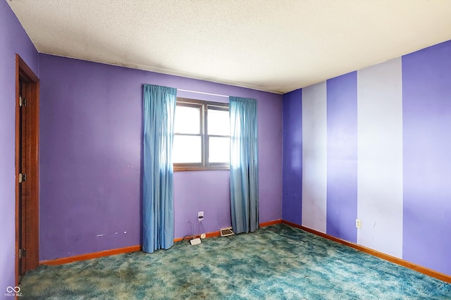 spare room featuring a textured ceiling and dark colored carpet