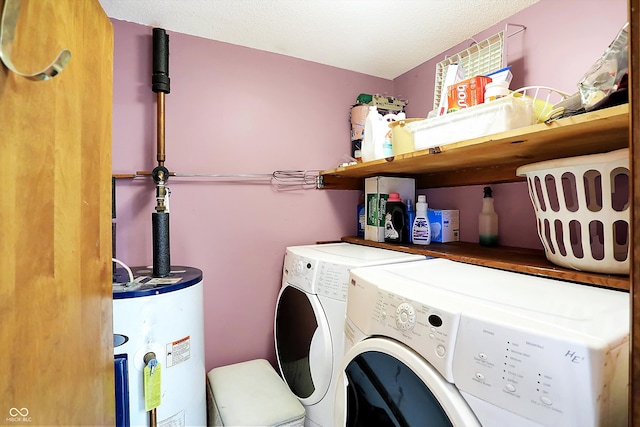 washroom with water heater, a textured ceiling, and separate washer and dryer