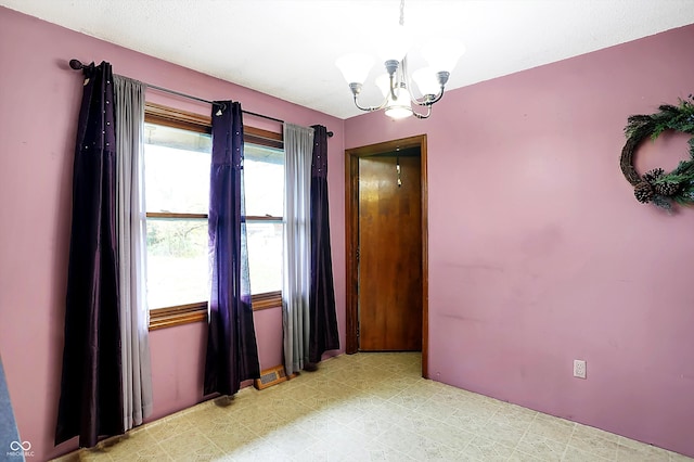 unfurnished room featuring an inviting chandelier