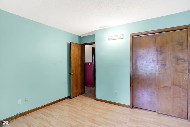 unfurnished bedroom with a closet, light wood-type flooring, and a textured ceiling