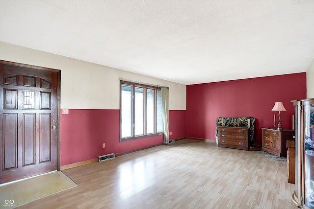 foyer entrance with light hardwood / wood-style floors and a textured ceiling