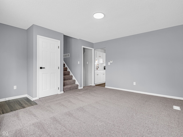 spare room featuring a textured ceiling and dark carpet