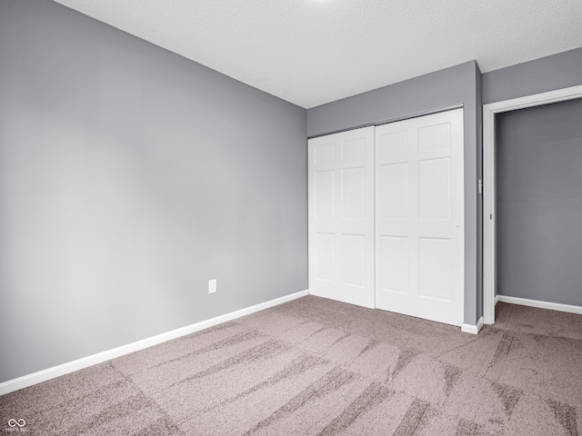 unfurnished bedroom featuring carpet flooring, a closet, and a textured ceiling