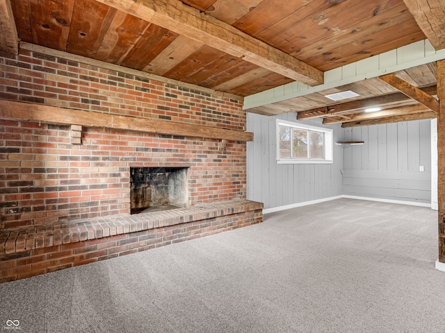 unfurnished living room with carpet floors, wooden walls, wooden ceiling, beamed ceiling, and a fireplace