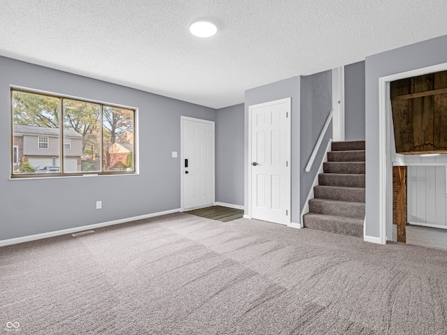 interior space featuring a textured ceiling and dark carpet