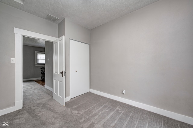 unfurnished room featuring carpet flooring and a textured ceiling