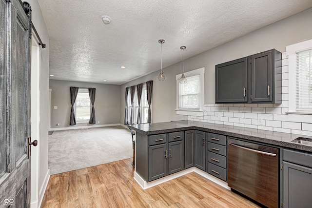 kitchen with stainless steel dishwasher, a wealth of natural light, a barn door, and light hardwood / wood-style flooring