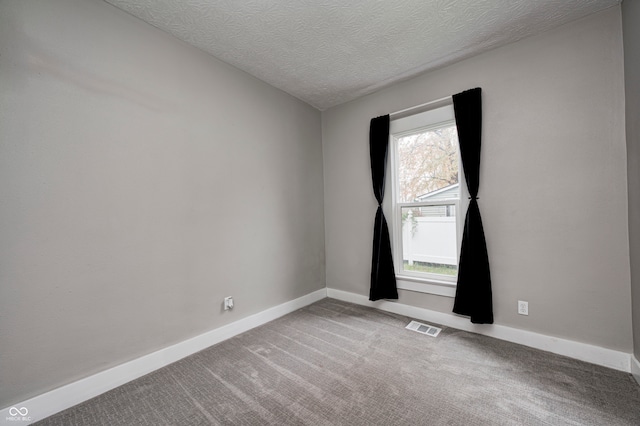 empty room with a textured ceiling and light colored carpet