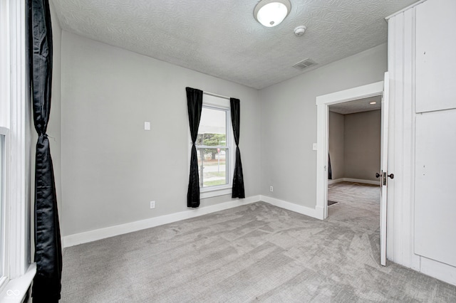 carpeted spare room featuring a textured ceiling