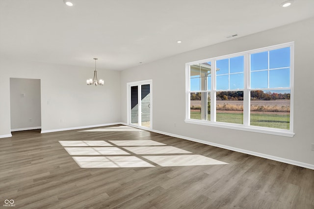 unfurnished living room with hardwood / wood-style flooring and a chandelier