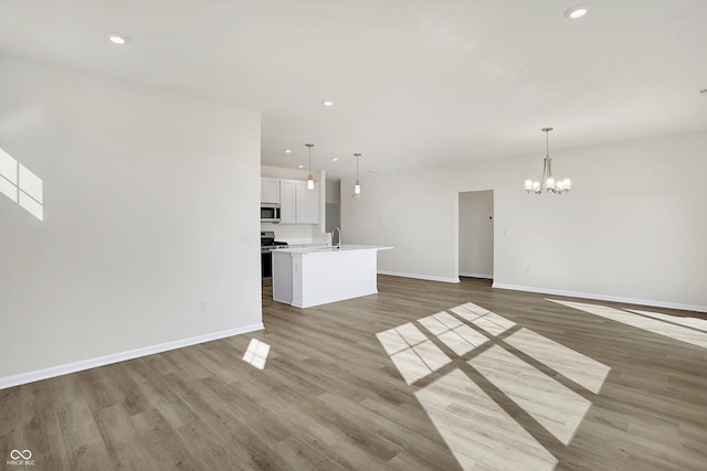 unfurnished living room featuring wood-type flooring, a chandelier, and sink