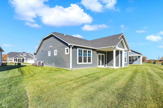 rear view of property with central AC unit, a garage, and a yard