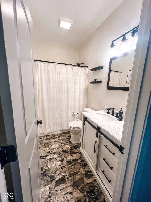 bathroom with curtained shower, vanity, and toilet