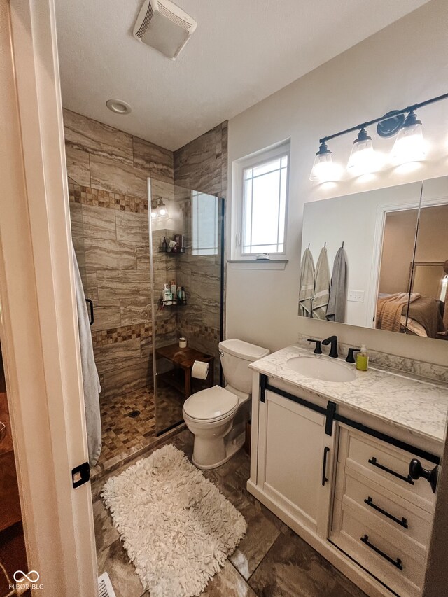 bathroom featuring toilet, vanity, and tiled shower