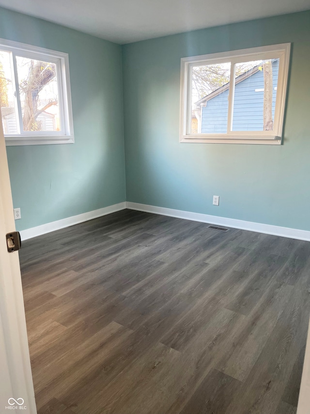 unfurnished room featuring dark wood-type flooring and plenty of natural light