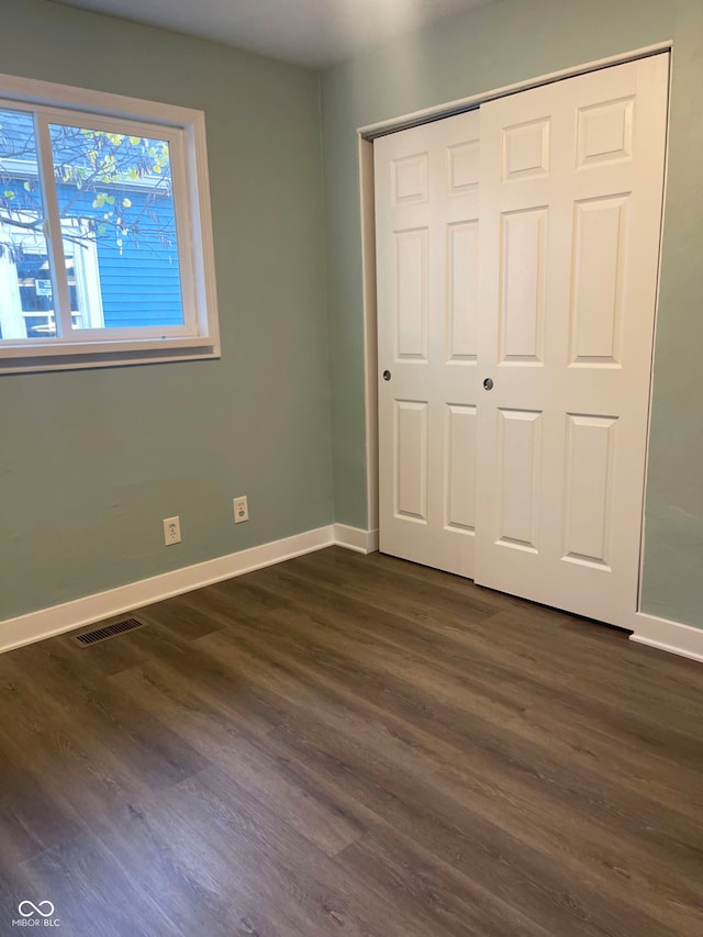 unfurnished bedroom with dark wood-type flooring and a closet