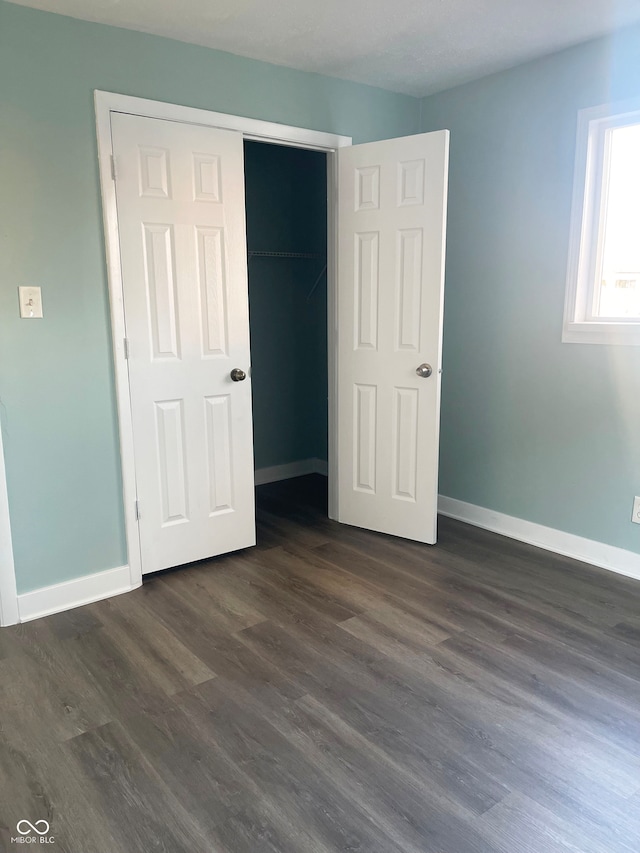 unfurnished bedroom with dark wood-type flooring and a closet