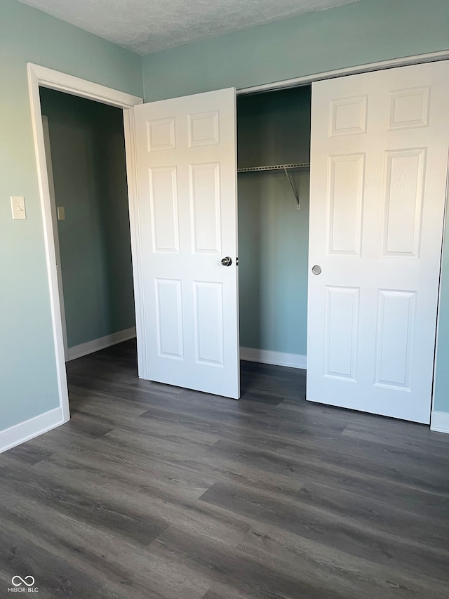 unfurnished bedroom featuring a textured ceiling, a closet, and dark hardwood / wood-style flooring