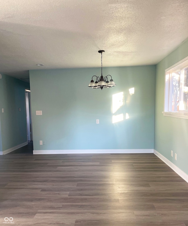 unfurnished dining area featuring dark hardwood / wood-style flooring, a chandelier, and a textured ceiling