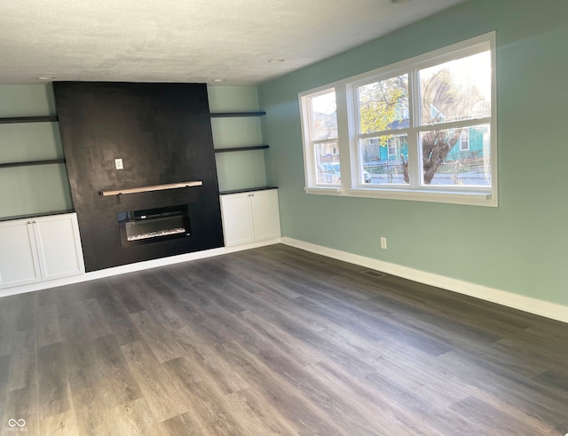 unfurnished living room featuring a fireplace, wood-type flooring, and a textured ceiling