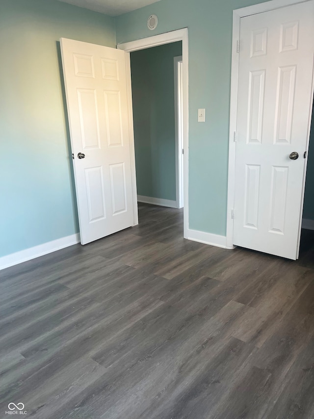 unfurnished bedroom with a closet and dark hardwood / wood-style flooring